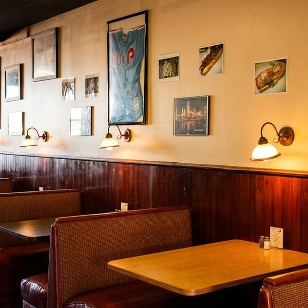 Cozy restaurant interior with dark wood paneling, booths, and framed pictures on the light-colored walls.